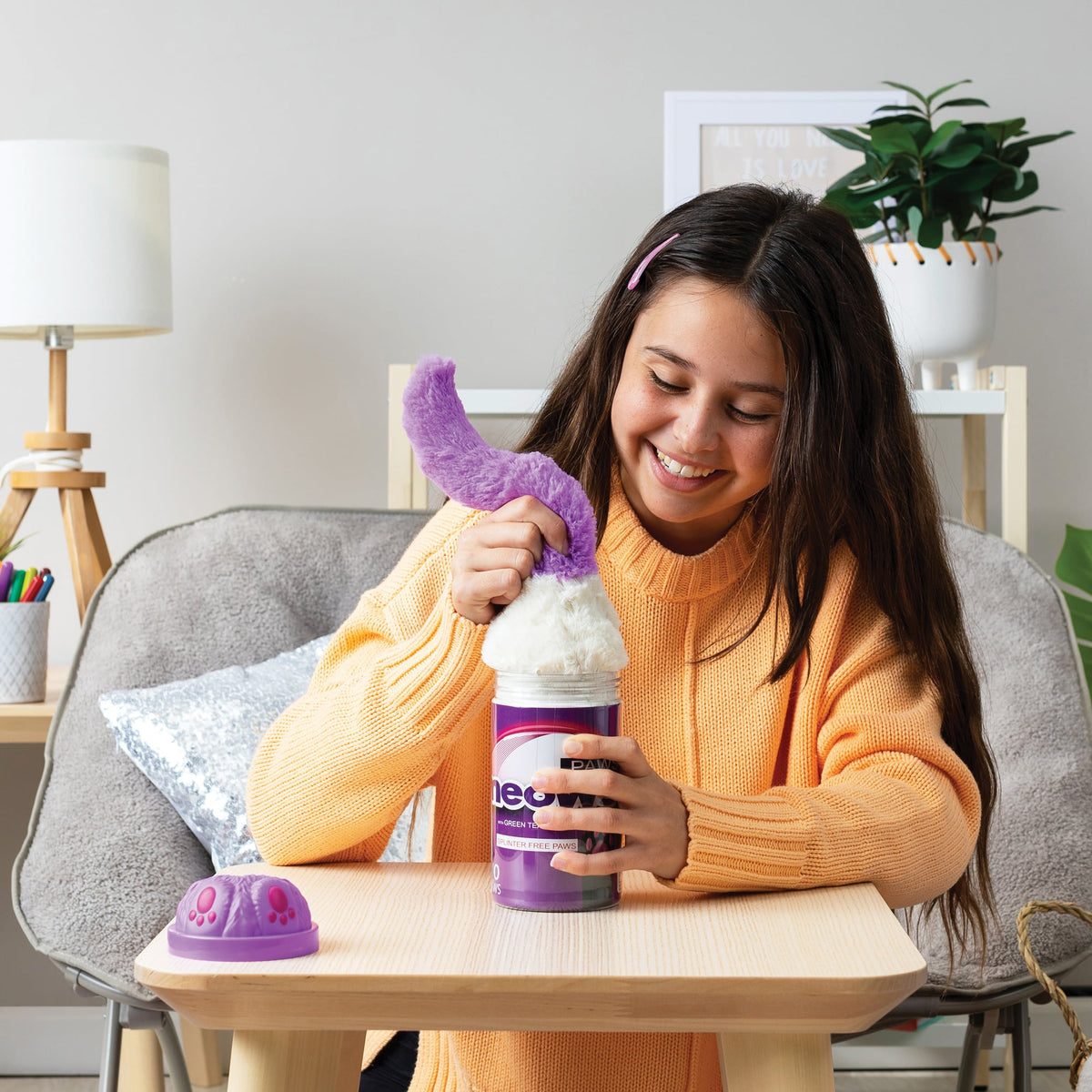 Girl pulling out the plush by the tail smushed into a purple Misfittens package